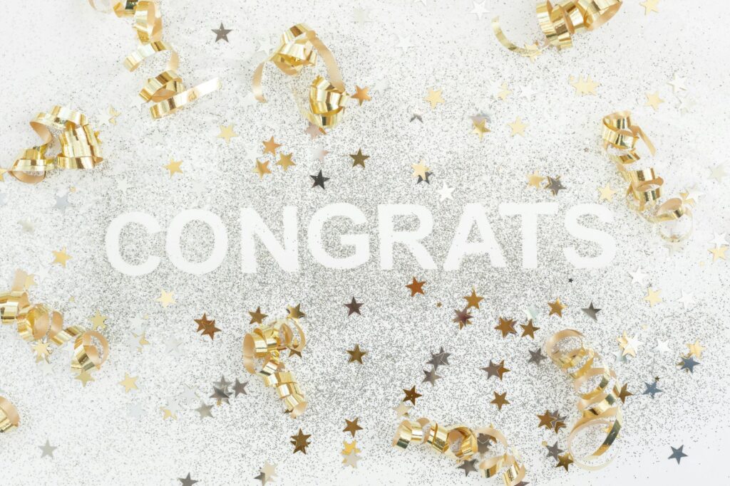 gold and silver confetti with the word congrats surrounded by confe